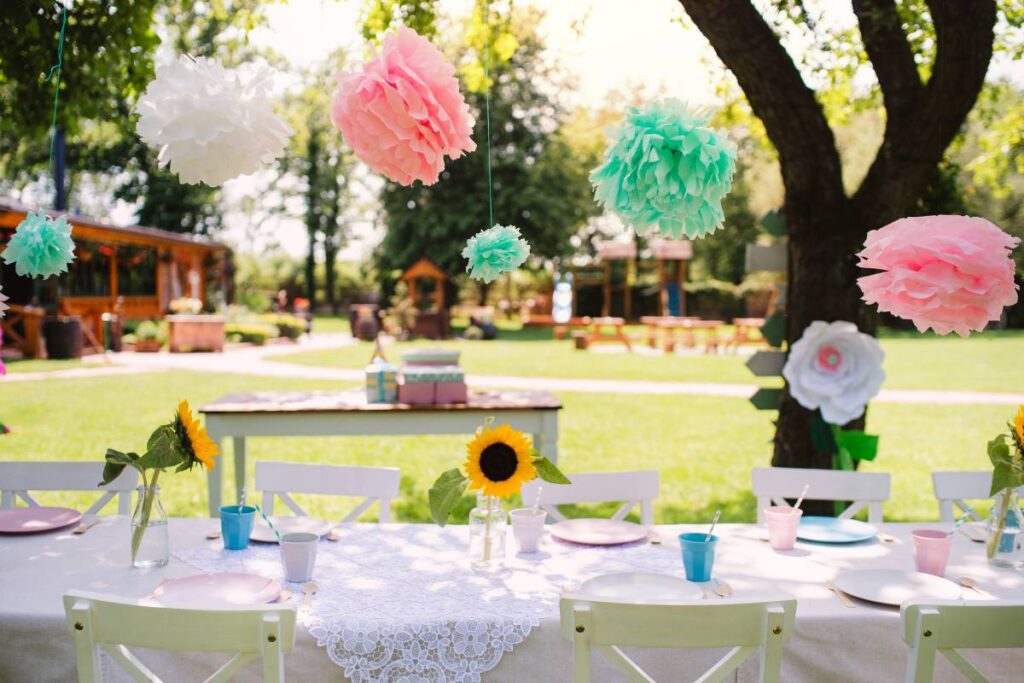 a festive set up with paper flowers strewn through the trees to host an outdoor event